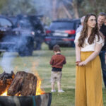 Photographie d'une jeune femme en train de se réchauffer les mains autour d'un feu