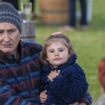Photographie d'une enfant souriante sur les genoux d'un monsieur